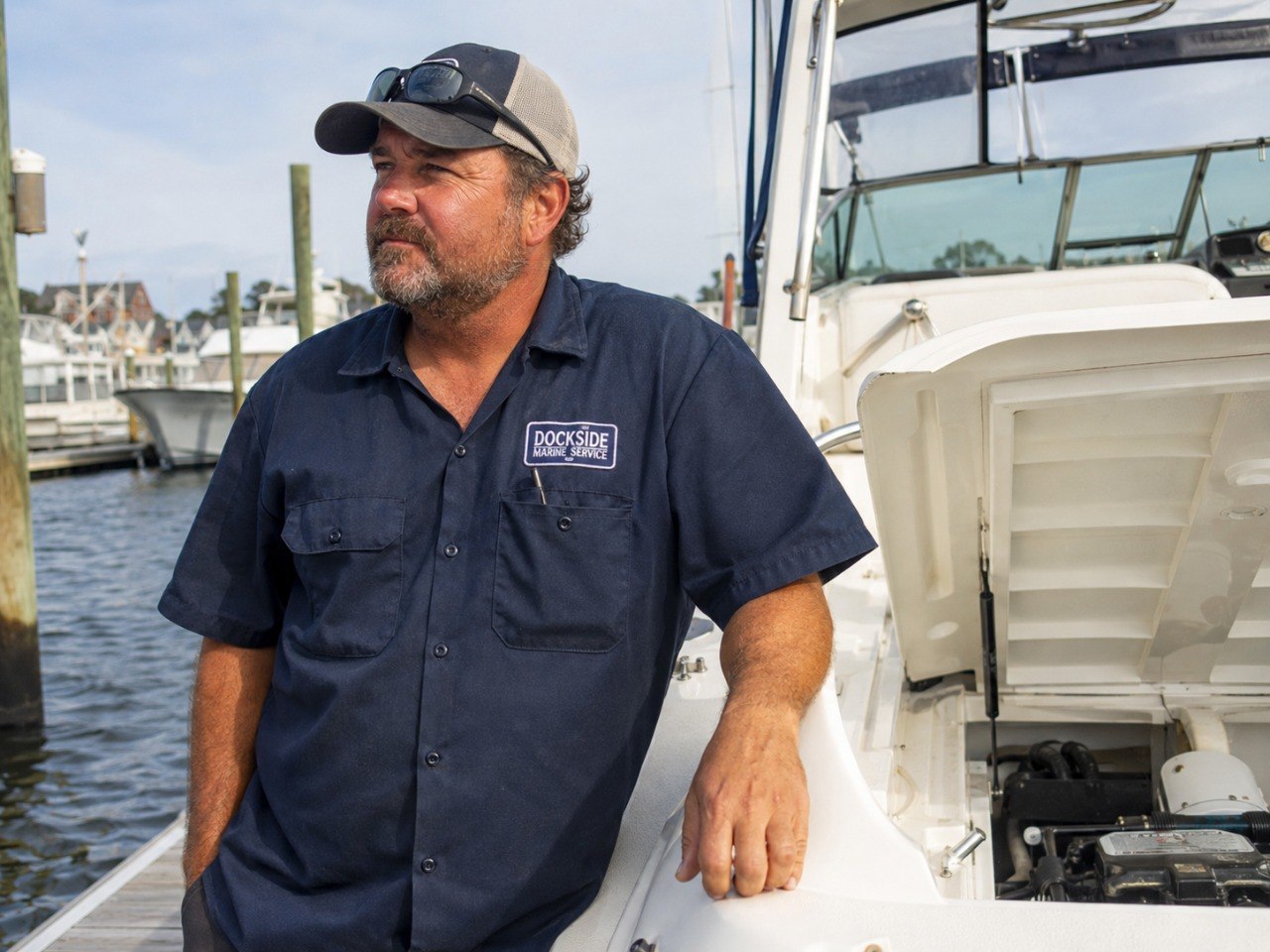 Marine service technician working near a boat at the dock.